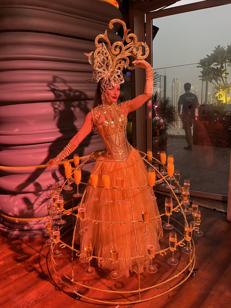 Elegant champagne living table artist serving guests at a luxury corporate event in Dubai.