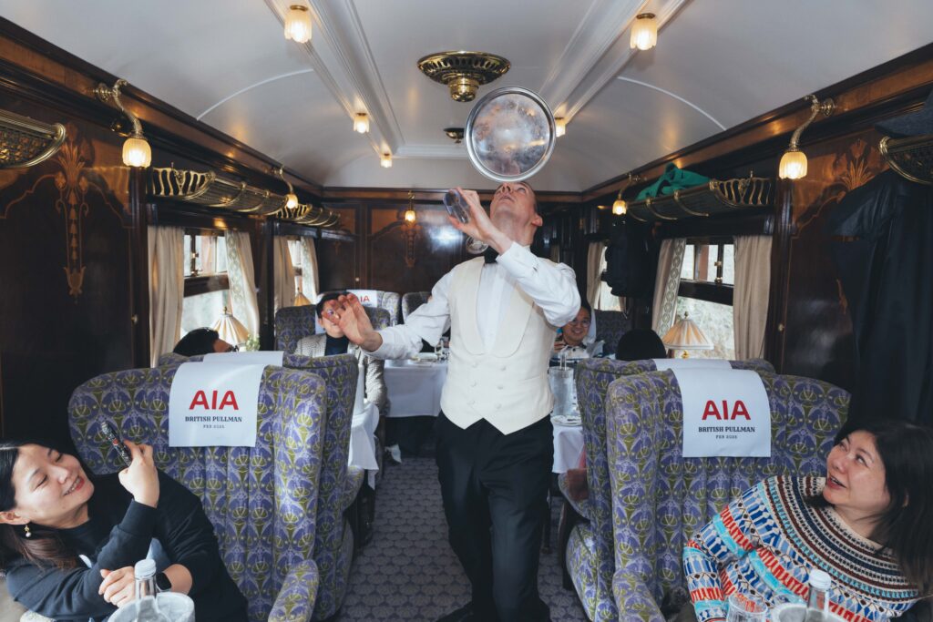 Artist juggling glasses on the British Pullman train for corporate entertainment in London.